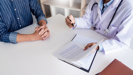 patient listening intently to a male doctor explaining patient symptoms or asking a question as...