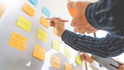 young business workers posting with sticky notes stickers reminders  creative brainstorming at board the colleague in a modern co-working space.