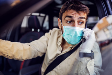 Fototapeta na wymiar Man with protective mask and gloves driving a car talking on mobile phone smartphone. Infection prevention and control of epidemic. World pandemic. Stay safe.