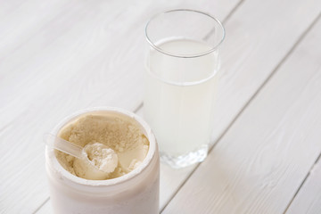  scoop of fish collagen. collagen peptides in container or jar. glass of water for mixing drink. Healthcare supplement concept. collagen powder for skin and joints .