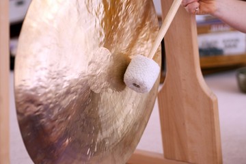Close up of a gong with a handheld stick during a sound healing therapy healing session. 