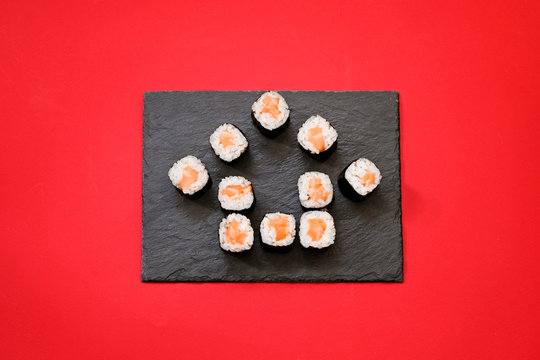 House shape sushi rolls on red background with copy space. Ordering sushi online at home while quarantine