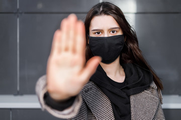 Young woman wearing face mask. Handsome woman in black hoodie wear black medical mask. Pandemic coronavirus covid-19 quarantine period concept.