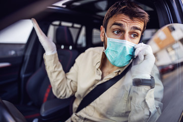 Fototapeta na wymiar Man with protective mask and gloves driving a car talking on mobile phone smartphone. Infection prevention and control of epidemic. World pandemic. Stay safe.