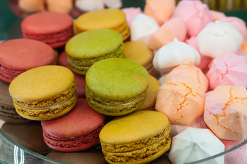 Colorful macaroons and meringue in cafe window. French sweet delicacies.