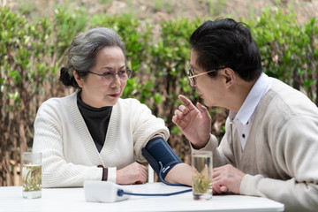 An Asian elderly couple is measuring blood pressure