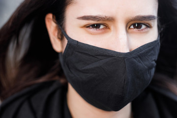 Young woman wearing face mask. Handsome woman in black hoodie wear black medical mask. Pandemic coronavirus covid-19 quarantine period concept.