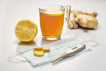 Fresh ginger root, lemone, tea, face medicine mask, thermometer on white background