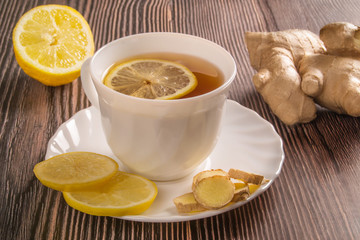 Fresh ginger root, lemon, tea on brown wooden table