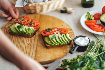 Cooking healthy sandwich with avocado and tomato at home in the kitchen. Top view