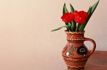 red tulips in clay vase