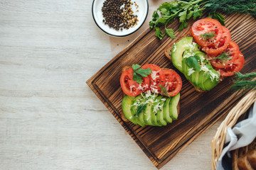 Healthy vegan homemade sandwich, avocado and tomatoes with dark grain bread on a wooden board.