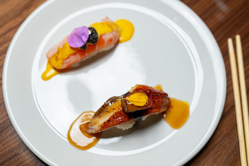 Sushi with eel and salmon on a white plate on a wooden table. The view from the top