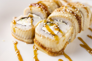Eel rolls with avocado, sauce on a plate close up