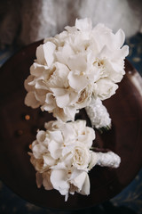 Wedding floristry. Bouquet of white flowers with a white ribbon lies on a wooden table