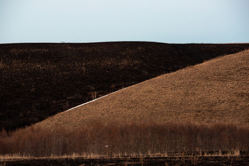 Burnt black earth as a result of artificial grass burning in the spring. Harm to nature.
