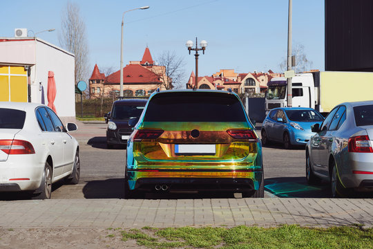 Chameleon holographic colour car on the parking among other cars. Unique bright colour vehicle. Custom paint wrap. Eye-catching concept photo.