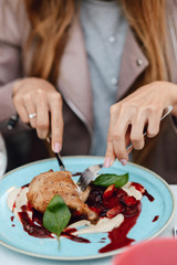 Female hands hold knife and fork, cutting off a piece of chicken.Soft focus