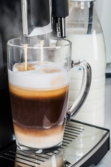 hot cappuccino from the coffee machine is poured into a glass Cup