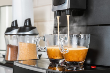 two glass cups with hot coffee from the coffee machine in the kitchen interior
