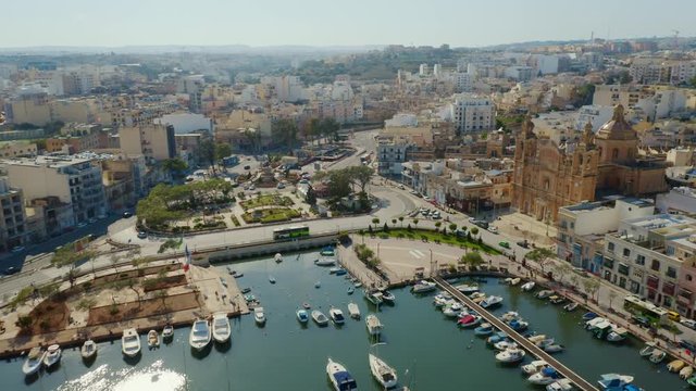 Aerial view of Msida marina, church, yachts, boats. Sunny day. Camera moves forward and turn. Malta island