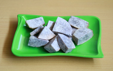 Boiled taro on green plate, wood background.