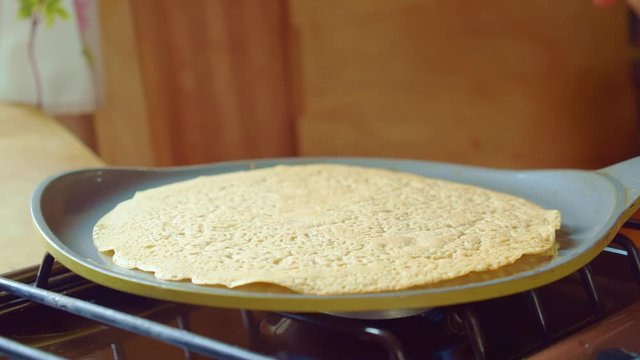 Cook flips delicious bake flapjack with spatula in frying pan. Close up. Slowmo.