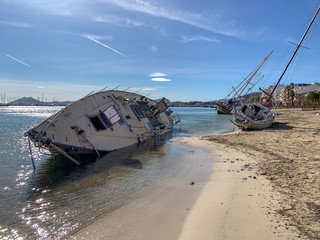 Several boats stranded on the beach after a storm. On a sunny day with few clouds. sailboat