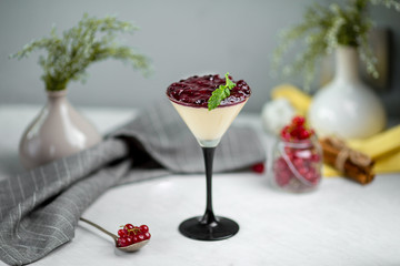 Side view on a sweet appetizing creamy mousse with berries jam in a glass on the white background, horizontal