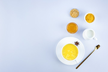 Golden milk and ingredients for cooking: turmeric, honey, ginger root, star anise, cinnamon on a gray with a copy space.
