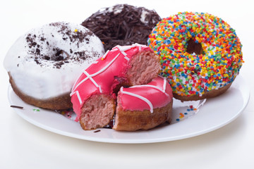 donuts with icing and chocolate in a plate on a white background