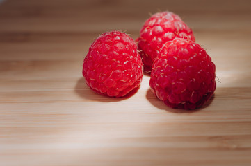 juicy fresh raspberries lie on the wooden surface