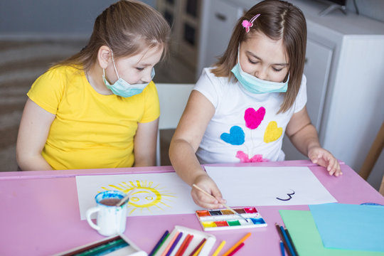 Girls drawing together at home during quarantine in sterile masks. Childhood games, drawing arts, stay at home concept