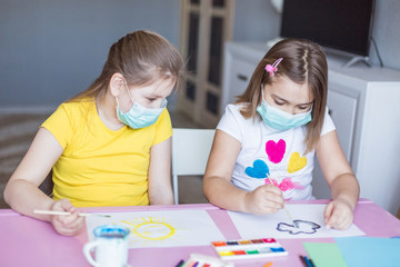 Girls drawing together at home during quarantine in sterile masks. Childhood games, drawing arts, stay at home concept