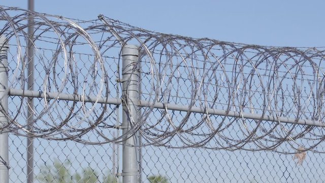 Slow pan across a barbwire fence outside an american jail