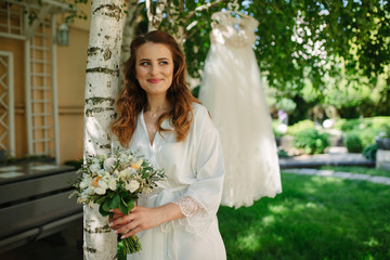 Pretty happy bride in luxury dress with bouquet of roses