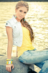 young woman sitting on the post near the river