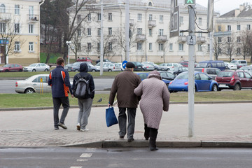 older people, old man and old woman hold hands and cross the street at a pedestrian crossing