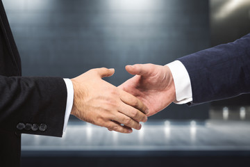 Handshake of two businessmen on the background of night exterior of the business center, partnership concept, close up