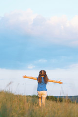 girl holding hands up in field
