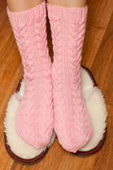 Fototapeta na wymiar woman feet in knitted pink woolen socks standing on fluffy slippers