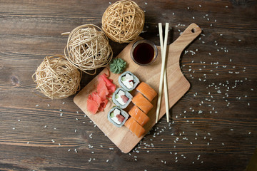 sushi philadelphia, rolls with tomato, cucumber and cheese on a wooden board with ginger, wasabi, soy sauce top view