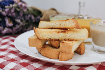 Piece of bread toast with dipping sauce on white plate.Thai Pandan mixed milk custard Custard & grilled bread. Bread with thai pandan custard Thai called Kanom Pang Sang Ka Ya.