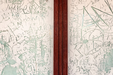Detail of door with white-painted glass and written scribbles, from a closed shop. Image of cessation of economic activity and confinement due to the covid-19 epidemic