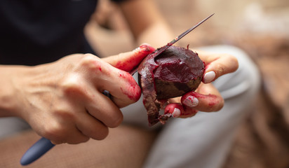 A girl peels cooked red beets with a knife