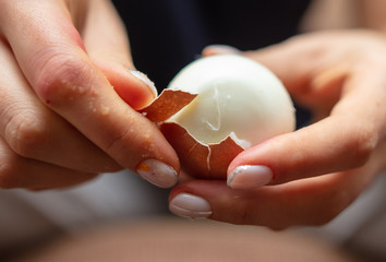 The girl is cleaning a boiled egg