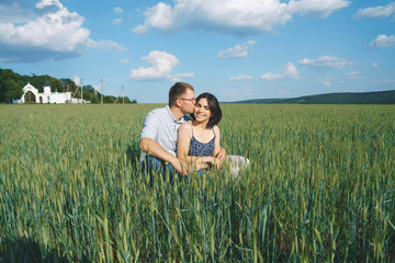 man kissing woman in cheek in grass