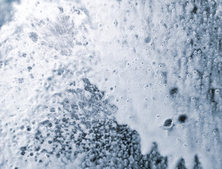 Auto glass in foam and water at a car wash as a backdrop