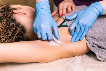 Waxing woman armpit. Salon wax beautician epilation procedure. Waxing female body for hair removal...