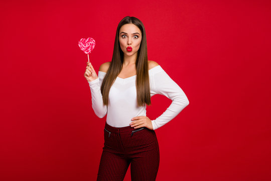 Portrait of romantic classy trend girl dream perfect 14-february dating send air kiss hold heart shape lolipop wear white checkered trousers isolated over bright shine color background